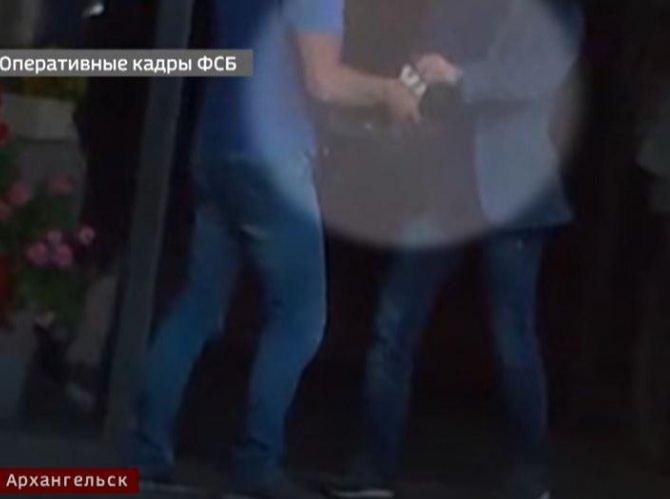Кузнецов кладёт деньги в сумку Магиду. Стоп-кадр видео «Вестей Поморья».